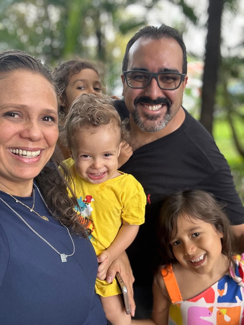 Lívia com o marido e os filhos, sorrindo ao ar livre