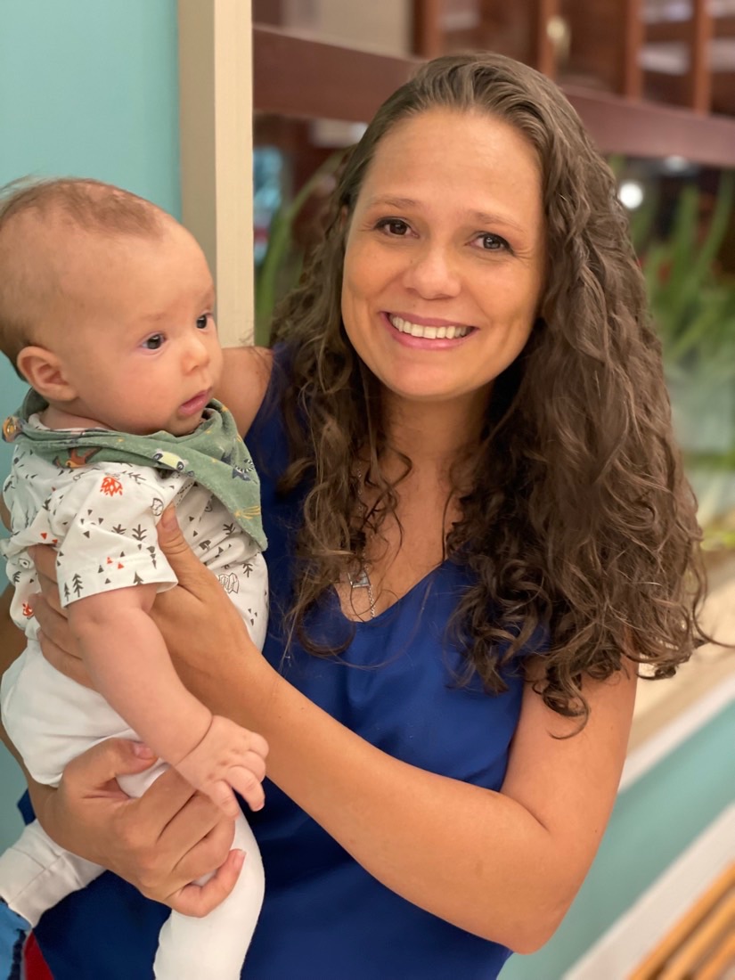 Retrato de Lívia sorrindo, com um bebê no colo
